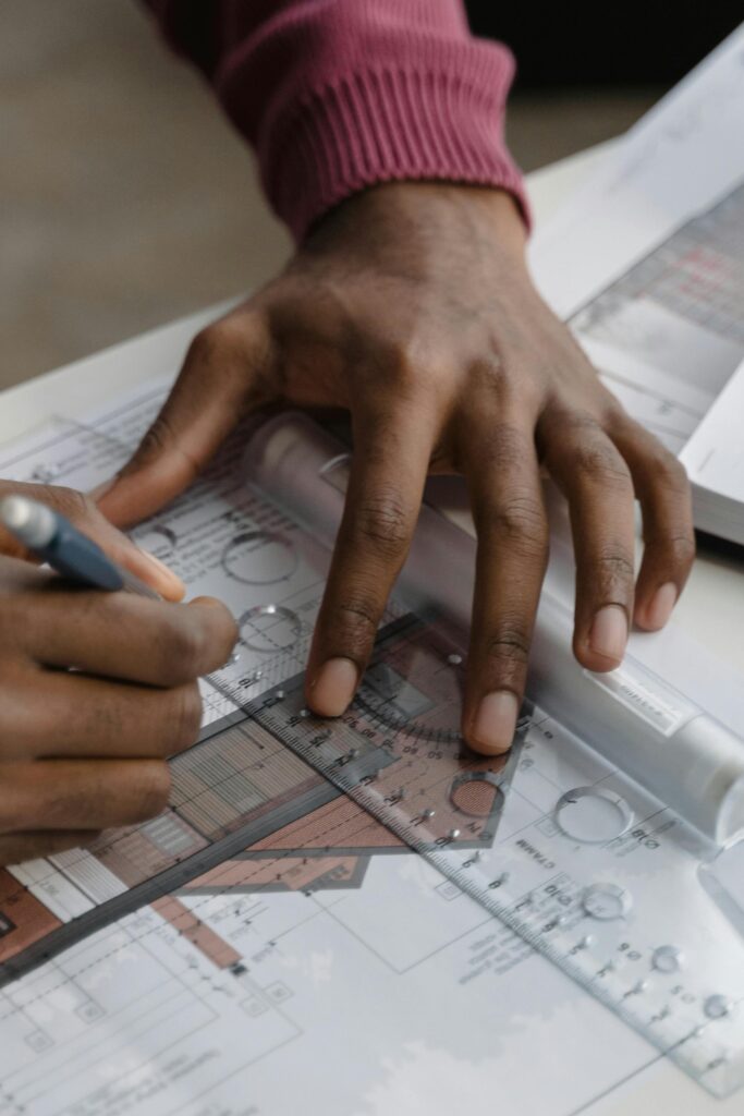 Close-up of a person sketching architectural floor plans with pencil, ruler, and paper.