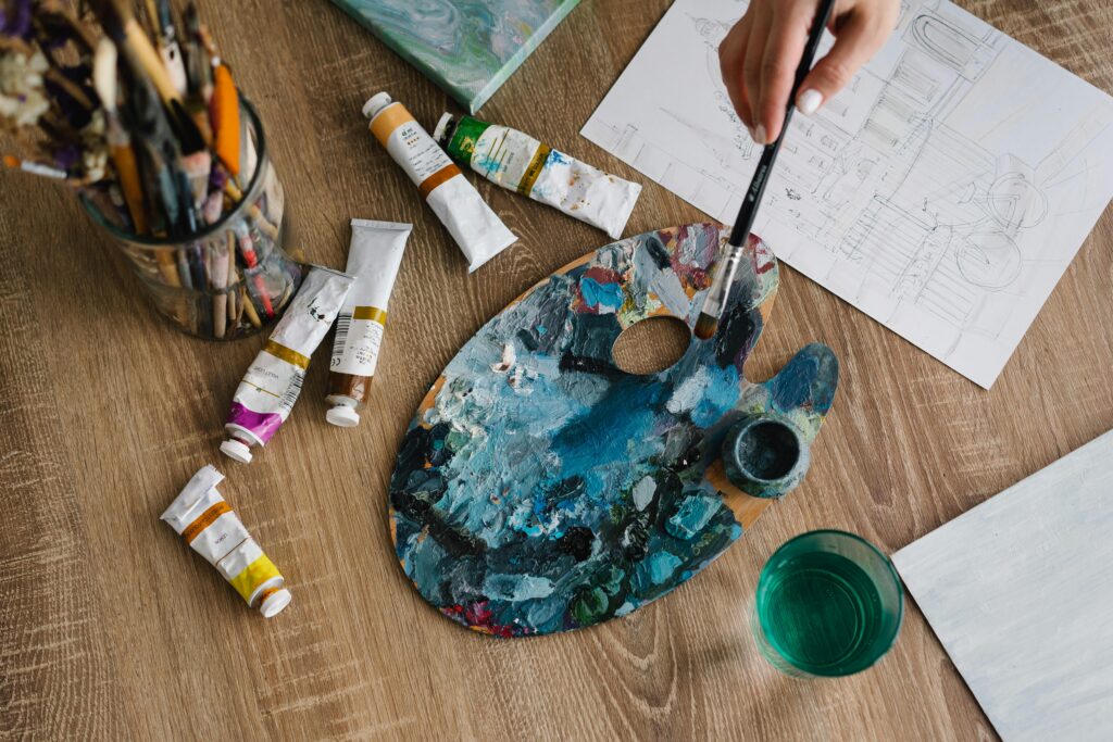 pexels-photo-6932377-6932377 An artistic setup with paint tubes, palette, and brushes ready for a creative painting session.
