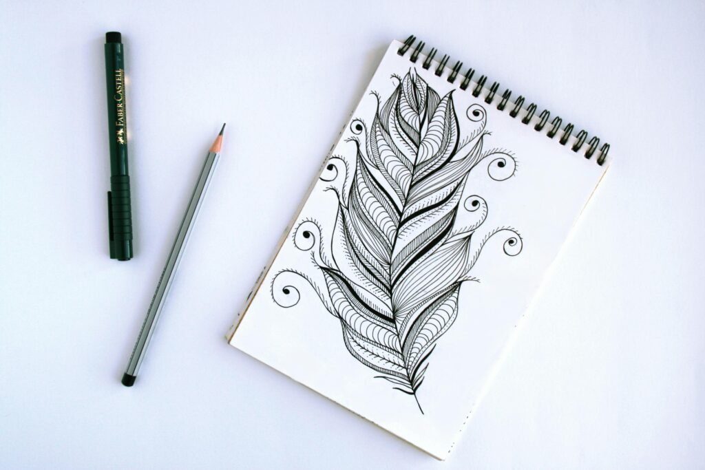 pexels-photo-826114-826114 Artistic feather sketch with pen and pencil on sketchpad, showcasing intricate details.