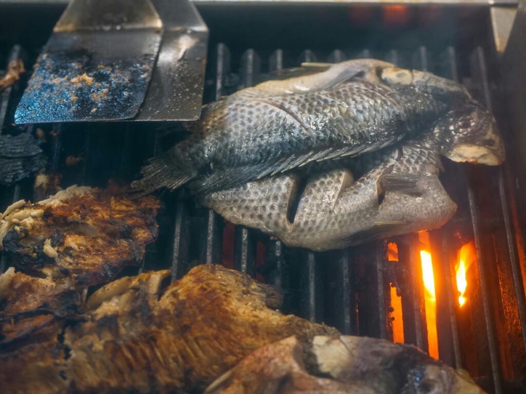 pexels-photo-8352777-8352777 Closeup of fresh tilapia fish being grilled on a charcoal grill, perfect for seafood lovers.